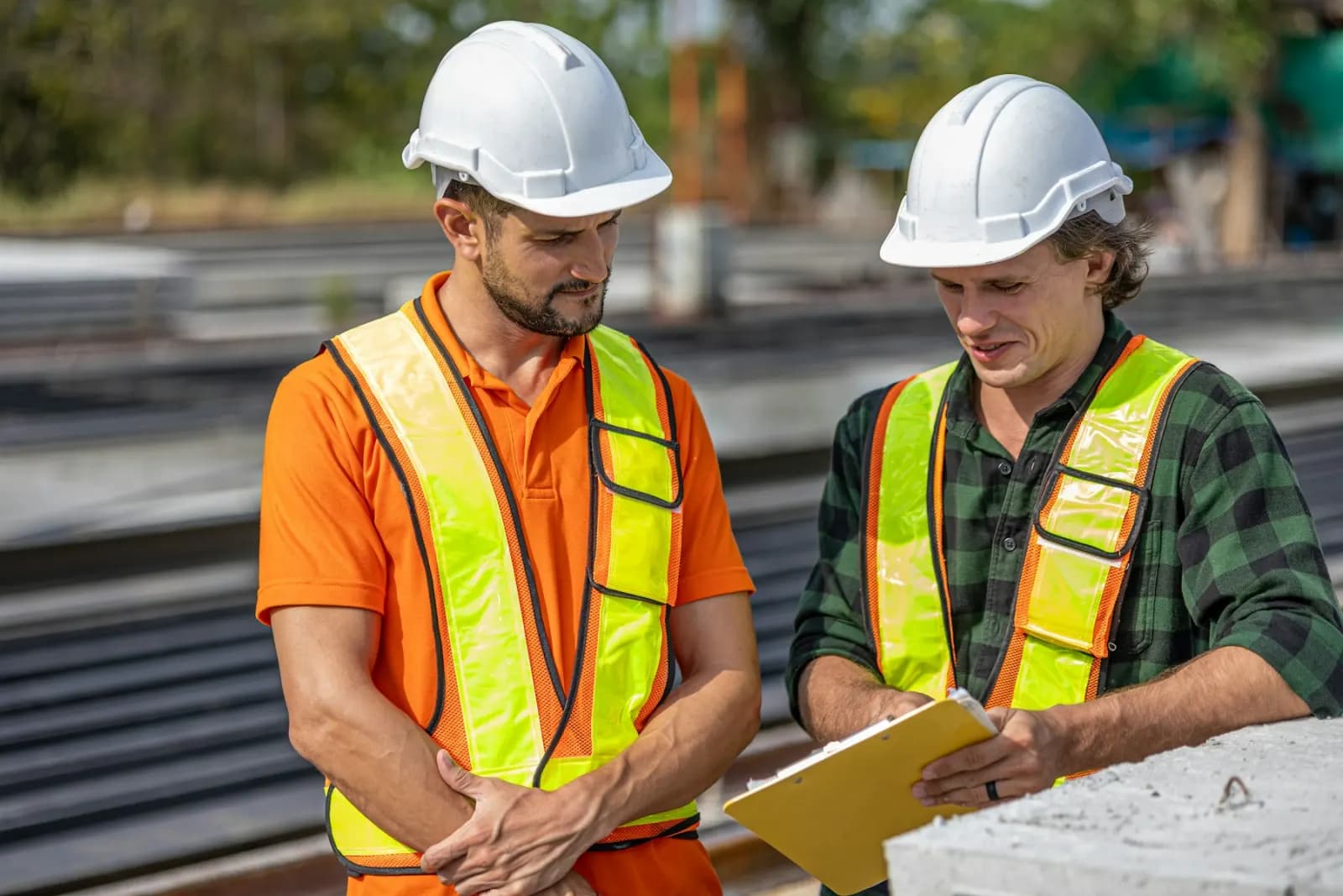 Construction workers reviewing a clipboard on a job site
