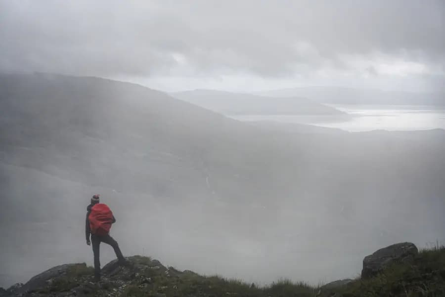A hiker standing in mist with a red backpack