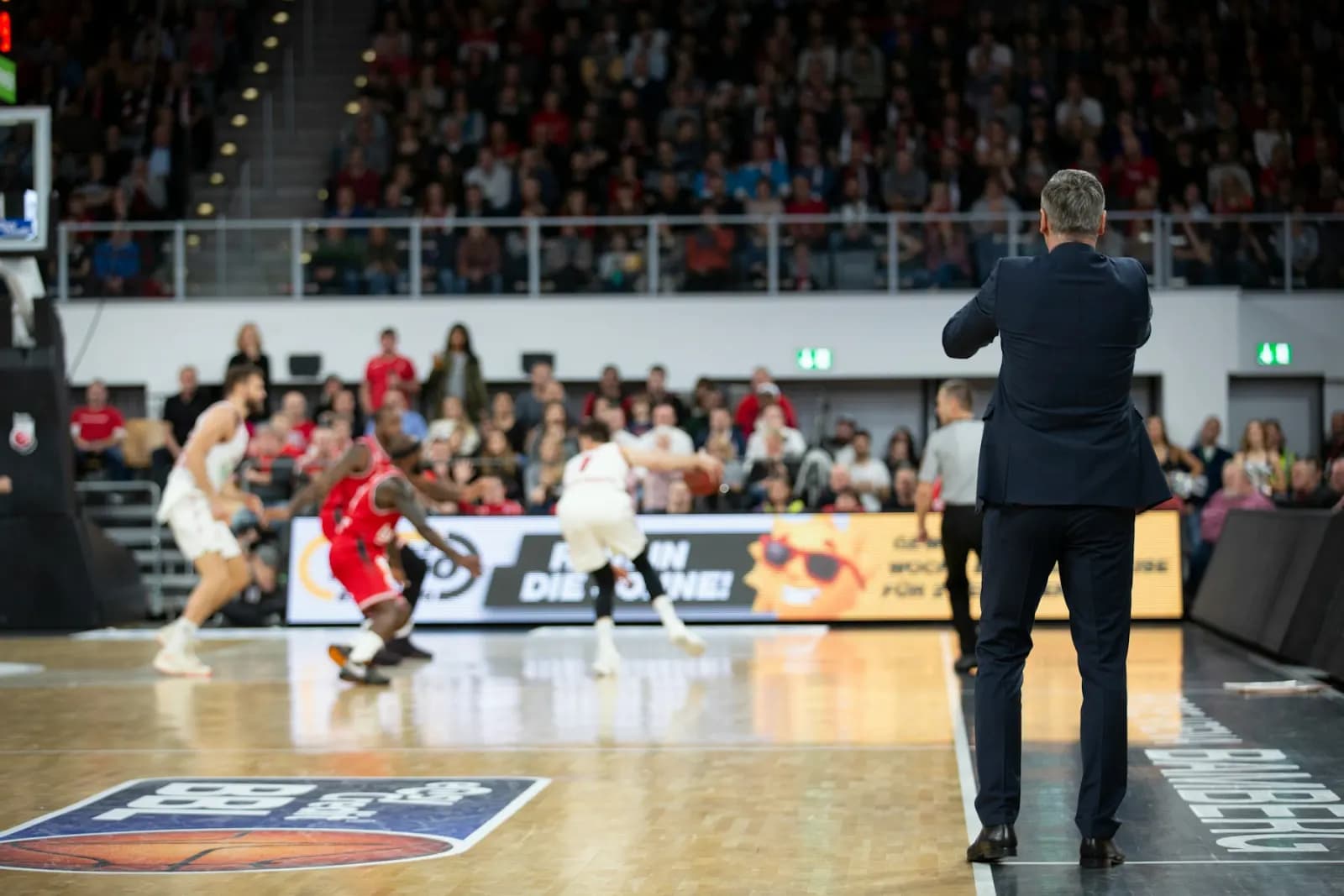 Basketball players competing under arena lights